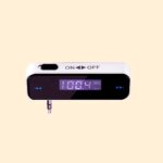 FM transmitter. Audio jack connection, an on off slide switch and frequency adjustment buttons are visible. as is an lcd screen displaying the current frequency range in MHz and the battery level